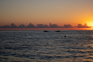 Beautiful panoramic view of the sunset over the Sochi sea with dark pink clouds and a view of the pebble beach.