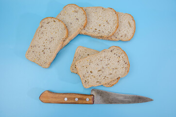 slices of rye bread with bran / knife on a blue background. View from above.