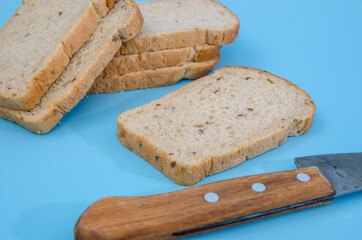 Close-up of slices of rye bread with bran / knife on a blue background. Sliced black bread