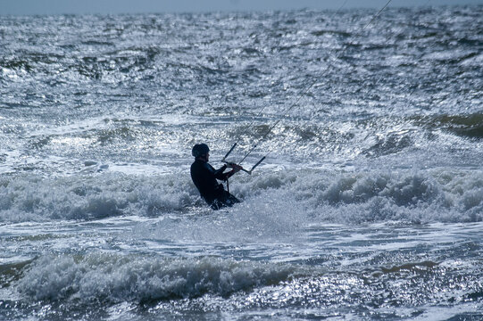 Kitesurfer als Silhouette vor silbern gl&auml;nzendem Meereshintergrund