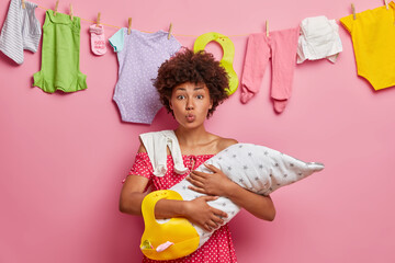 Caring beautiful young mother with her three month old baby keeps lips rounded wants to kiss her...