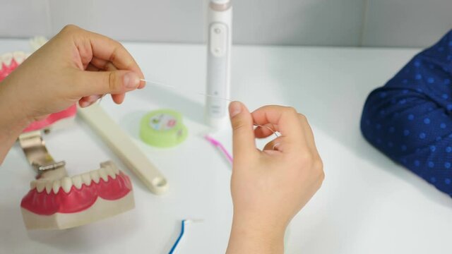 Orthodontist showing how to clean teeth using dental floss and jaw model. Hands holding teeth cleaning thread. Flossing teeth. close-up. Dental oral hygiene. 4 k video