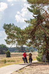 Fototapeta na wymiar Couple of bikers standing under a tree in National Park De Hoge Veluwe, Gelderland, in he Netherlands