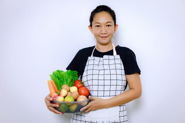 Fototapeta premium Asian Woman Standing Smile and Holding Mix Freshness Vegetables Box. Home Food Cooking and Housework Concept.
