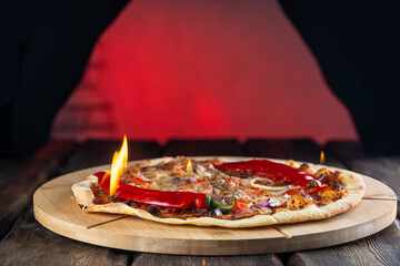 hot tasty pizza with fire flames on wooden cutting board, close view 