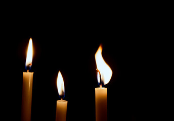 lighting candles, Burning candle on black background, Candle in hand, Candle in the dark, Design for the background. The light of the yellow stick candle in the dark at night.