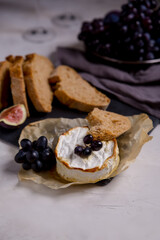 camembert cheese with figs, grapes and bread on the table. Wine appetizer. brie cheese. Vertical background. Copy space.