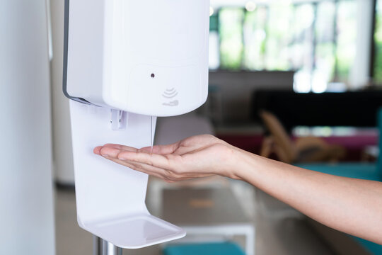Close up of woman's hand using alcohol gel disinfecting hands. Cleaning, washing hands using automatic sanitizer dispenser concept.