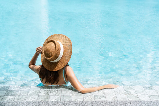 Carefree Asian female relaxing in swimming pool at spa resort. Summer an d holiday concept. Rear view, close up