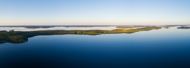 Panoramic view of sunset over the lake in nation park. Amazing landscape of Paijanne lake with crystal clear water and Perfect blue sky. Drone shot.