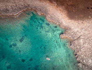Aerial shot of a boat sailing near the island of Capo Passero. It's a small island in the southernmost Sicily, Italy