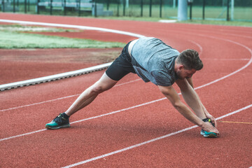 Obraz premium Young Caucasian man doing stretching exercises, open legs