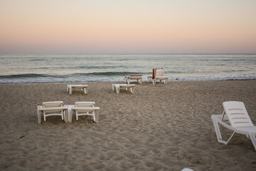 Fototapeta na wymiar Beach chairs. End of the beach season, plastic beach deck chair on an empty beach at sunset.