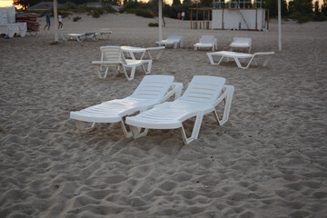 Beach chairs. End of the beach season, plastic beach deck chair on an empty beach at sunset.