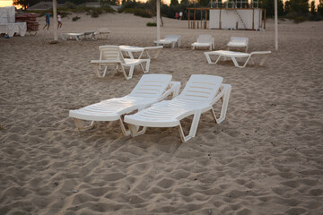 Beach chairs. End of the beach season, plastic beach deck chair on an empty beach at sunset.