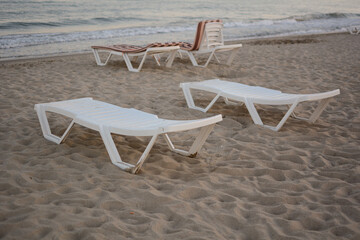 Fototapeta premium Beach chairs. End of the beach season, plastic beach deck chair on an empty beach at sunset.