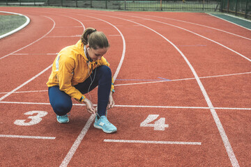 Young Caucasian woman squatting and tie her shoelaces