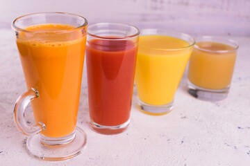 Glasses with fruit and vegetable juices on a white background.