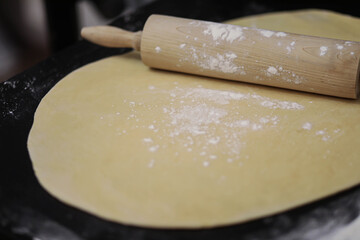 Dough and rolling pin on the table, roll out the dough with flour rolling pin