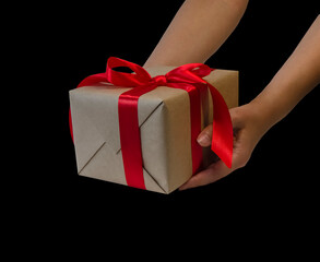 hands hold gift box with red ribbon, copy space isolated on black. Sales concepts, discount price, christmas gifts and shopping, greeting card for christmas, valentine's day or new year
