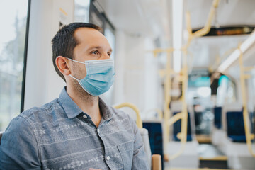 Fototapeta na wymiar Young man traveling by bus with a mask during pandemics.