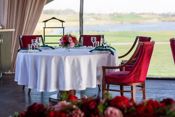 Beautiful flower arrangement of red flowers in the restaurant. Burgundy chairs