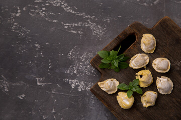 Homemade raw italian tortellini on a dark background with place for text. Copy space
