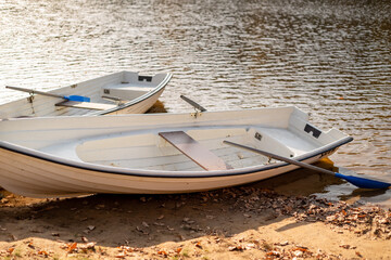 Two old boats with oars lay on the lake shore on lake water ripples background