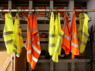 yellow work vests are hanging on a hanger.