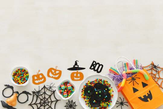 holidays image of Halloween. Pumpkins, bats, treats over white wooden background. top view, flat lay