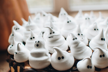 Sweets for halloween party on a wooden table. Halloween style party, candy bar and decorations with pumpkins. Halloween cake and ghost shaped meringue.