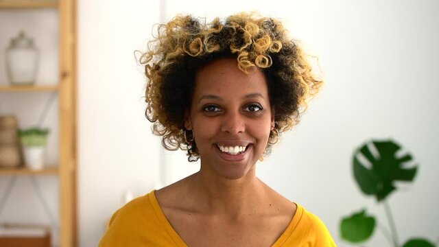 headshot of African woman smiling indoors Spbd. female with bleached curly hair look at camera, portrait. casual young woman student individuality. concept apartment