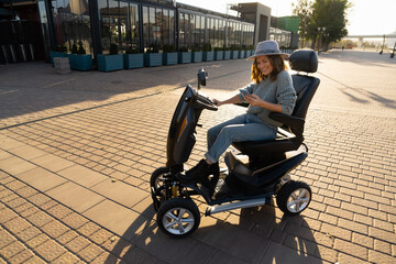 Woman tourist with smartphone on a four wheel mobility electric scooter on a city street.