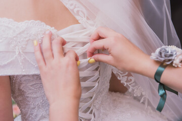 Obraz na płótnie Canvas Corset lacing on white bride dress close up