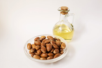argan tree nuts (Argania spinosa) on a white background with a bottle of oil.