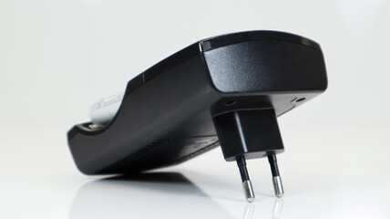 Fast charging of AA batteries. Rechargeable batteries in a black charger with four battery cells on a white background.