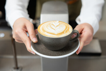Close up shot of barista girl hands serving nice hot latte art coffee.