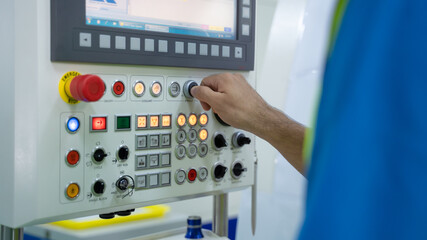 Closeup hand of engineer turning switch on machine panel in factory.