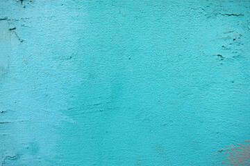 Turquoise background of the color of the sea wave, the wall of a residential building with small cracks and texture