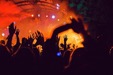 Abstract blur atmosphere: happy people enjoying outdoor music festival concert, raised up hands and clapping of pleasure, active night life concept, play of light and shadow on the stage