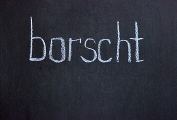 
The word "borscht" on a dark board. Culinary lettering