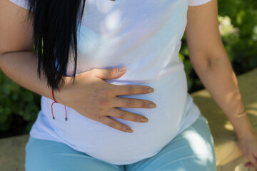 A young pregnant woman holds her hands on her tummy and feels the tremors of her baby