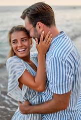 A loving young couple hug on the seashore, enjoying each other and their vacation, romantically spending time on the beach.