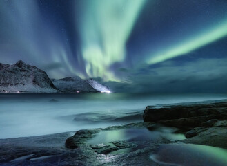 Obraz na płótnie Canvas Aurora borealis on Lofoten islands, Norway. Green northern lights above mountains. Night winter landscape with aurora. Natural background in the Norway.