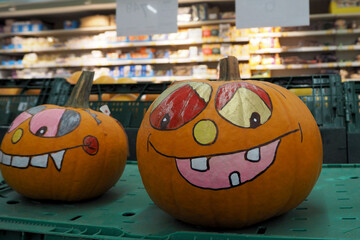 two orange pumpkins painted with Halloween colors in the supermarket