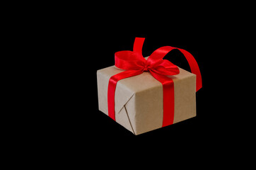 Obraz premium Gift box with red ribbon, copy space isolated on black background. Sales concepts, discount price, black friday, christmas gifts and shopping, greeting card for christmas, valentine's day or new year 