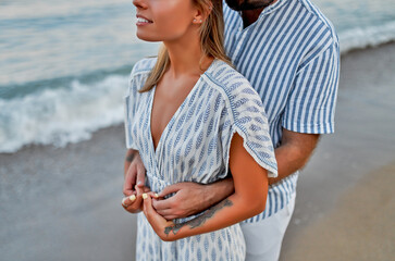 Close-up cropped image A loving young couple hugging on the seashore, enjoying each other and vacation, spending time romantically on the beach.