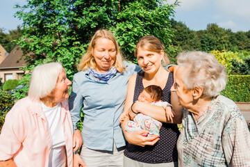 Women of happy multi-generational family with newborn girl outdoors