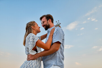 Young couple in love hug on a background of blue sky, romantically spend time enjoying each other and vacation.