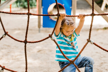 Toddler girl at playground climbing on jungle gym